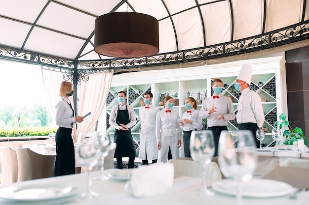 Employees of a Restaurant or Hotel in protective masks. End Of Quarantine. Restaurant Manager and his staff on the terrace. interaction with the chef in the restaurant.