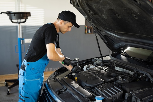 Empowering male mechanic is working in car service man is working on an usual car maintenance