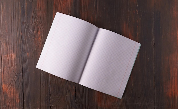 An empty A4 notebook in expanded form on a wooden textured background top viewmockup