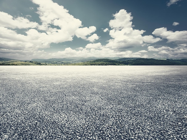 Empty asphalt pavement and mountains without cars and no one under the blue sky