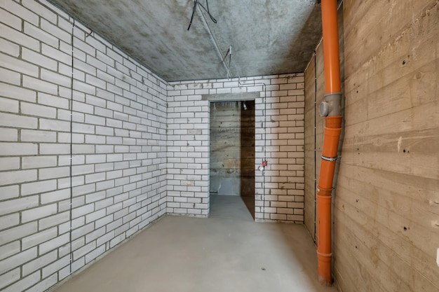 Empty basement room with minimal preparatory repairs interior with white brick walls