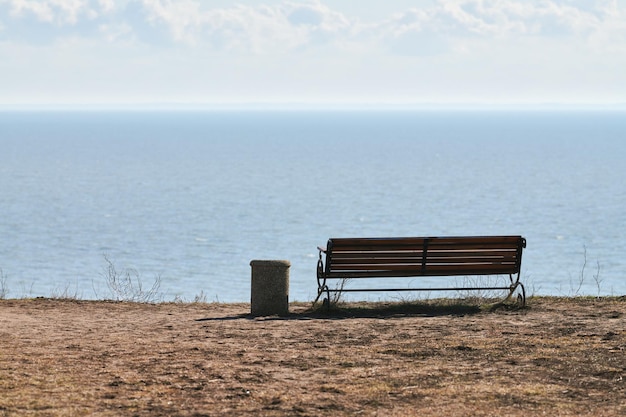 Empty bench with trashcan on cliff before sea background peaceful quiet place for thinking alone