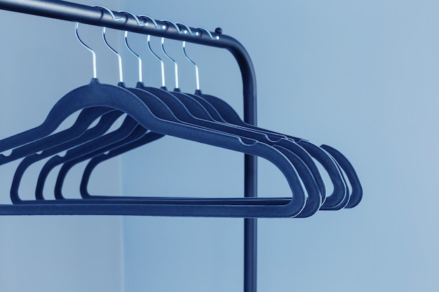 Empty black clothes hanger on blue wall background