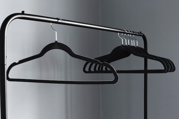 Empty black clothes hanger on gray wall background