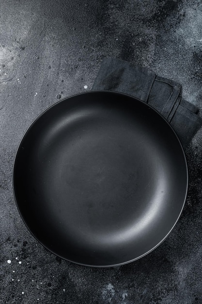 Empty black craft plate on table Table setting Black background Top view Copy space