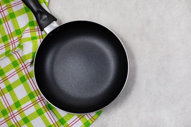 Empty black frying pan with green kitchen towel