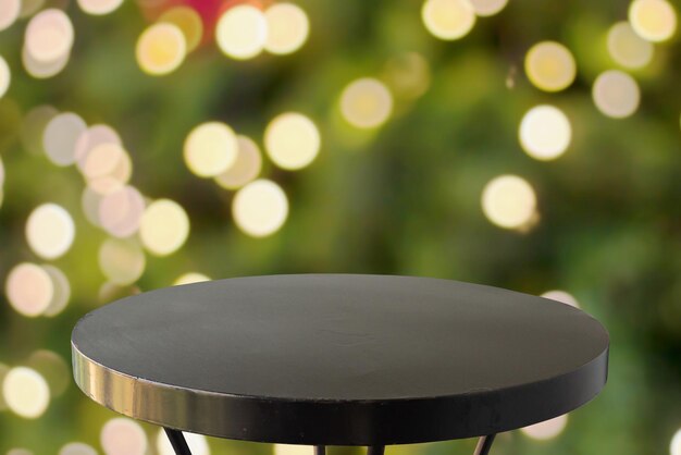 Photo empty black round table top with blur christmas tree with bokeh light background