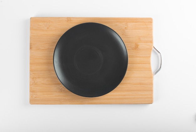 An empty black saucer on wooden board