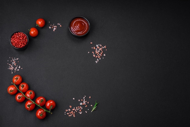 Empty black texture table cherry tomatoes on a twig spices salt and herbs