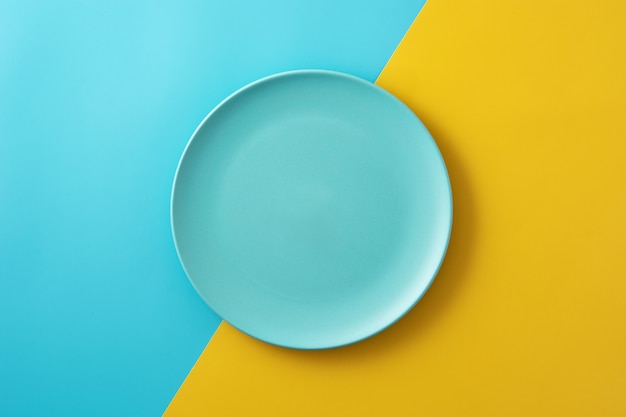 Empty blue plate on yellow and blue table