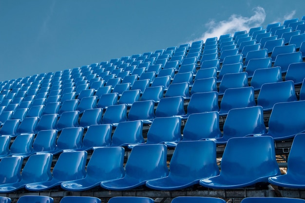 Empty blue seat in football stadium with blue sky