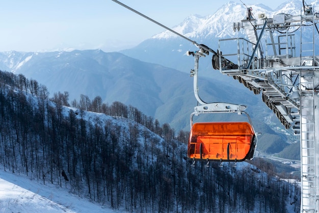 Empty bright orange ski chair lift in mountains winter against snow Alpine skiing and snowboarding