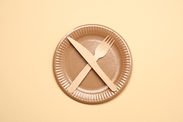 Empty brown paper plate and wooden knife and fork