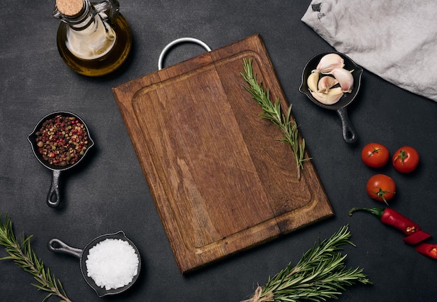 Empty brown wooden board and spices on black table top view