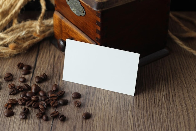 Photo empty business card mockup with coffee beans and vintage grinder on wooden table background mock up for branding identity blank template for your design