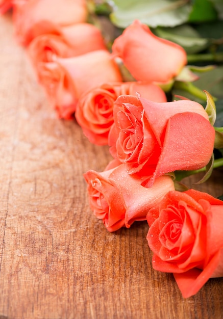 Empty card form and bouquet of rose with green leaves on a wooden