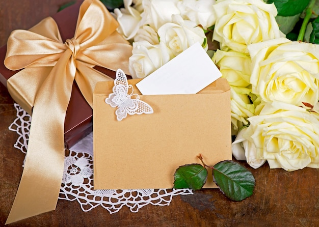 Empty card form and white rose bouquet of white rose with green leaves on a wooden