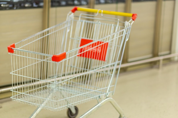 Empty cart on wheels for groceries in a hypermarket on a blurred background