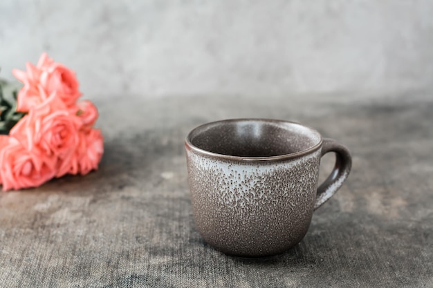 Empty ceramic coffee cup and a bouquet of roses on the table Time for a break and relaxation