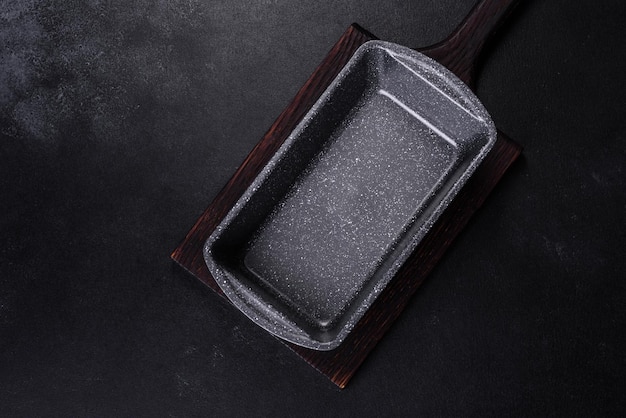 An empty ceramic grey baking dish on a dark concrete background Preparation for baking tasty cupcake