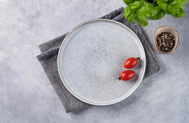 An empty ceramic plate on a blue background with a tomato spices and fresh basil The concept of healthy food