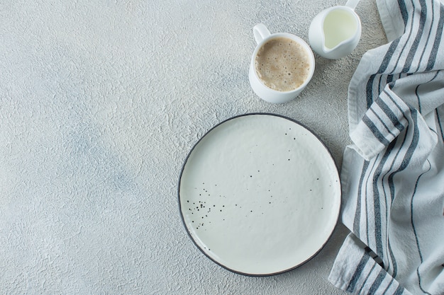 Photo empty ceramic plate, cup of coffee and kitchen striped towel