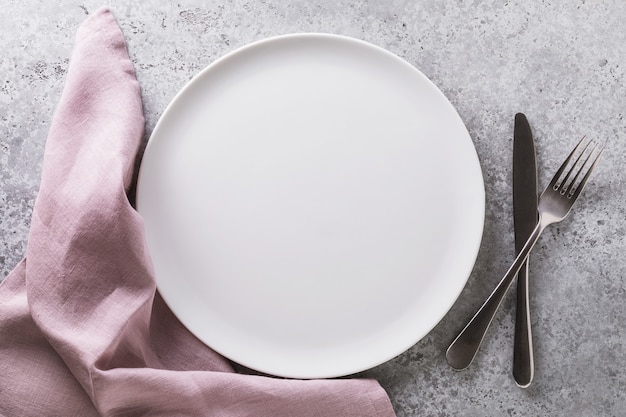 Empty ceramic plate white napkin and cutlery on the table top view