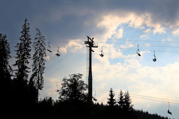 Empty chairs of the cableway at the mountain resort in a sunset