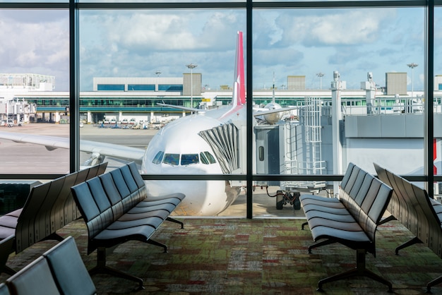 Empty chairs in the departure hall at airport with airplane parking. 