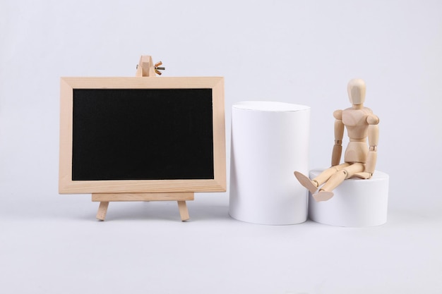 Empty chalk board with wooden puppet and geometric shapes on white background School composition Copy space