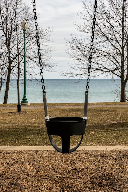 Photo empty childs chain swing with the view of a lake and the  change of season