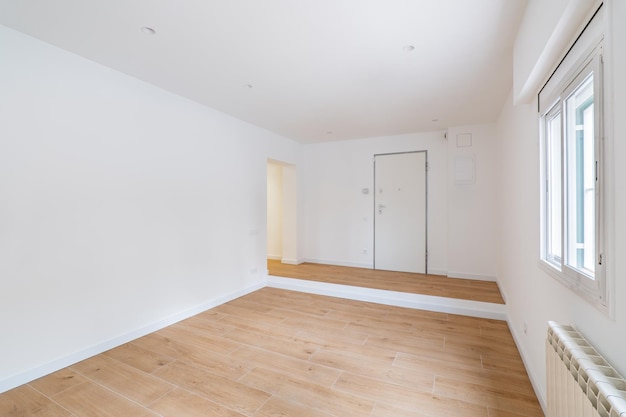 Empty clean room after renovation with white walls window and wooden floor