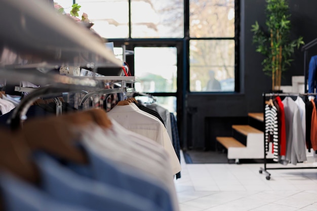 Empty clothing department store in shopping mall, new fashion collection on shelf. Fashionable clothes on hangers and accessories, modern boutique with merchandise at sale for customers