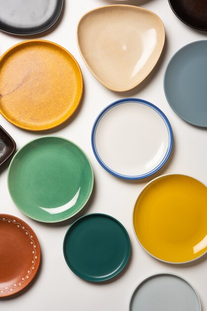 Empty colourful ceramic plates in group over white background, top view