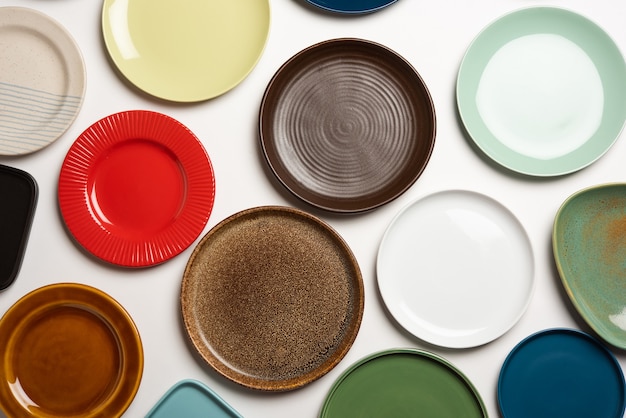 Empty colourful ceramic plates in group over white background, top view