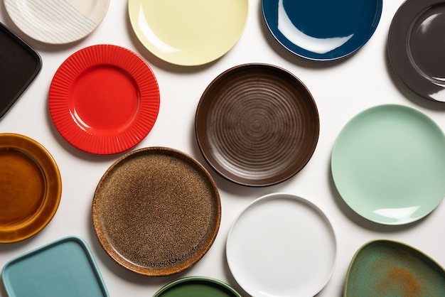 Empty colourful ceramic plates in group over white background, top view