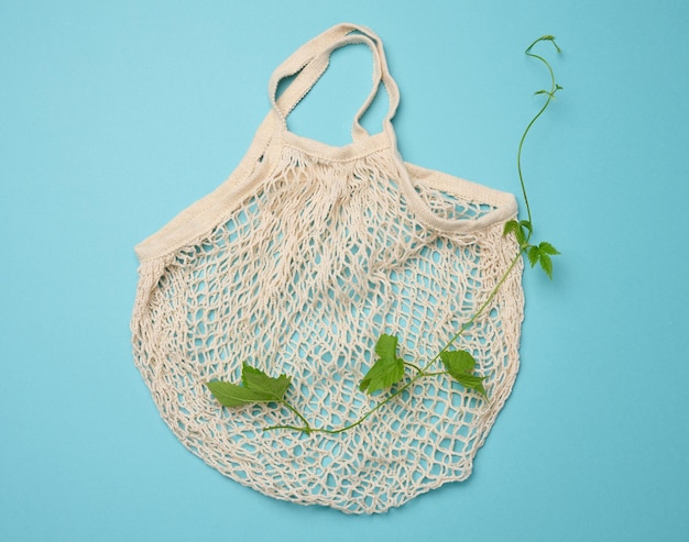 Empty cotton reusable bag on blue background Refusal of plastic