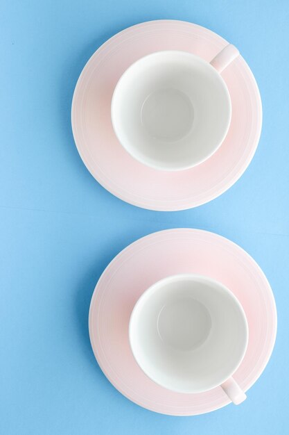 Empty cup and saucer on blue background flatlay