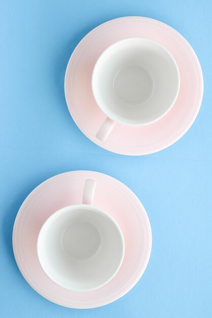 Empty cup and saucer on blue background flatlay