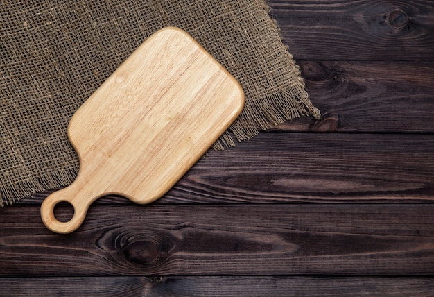 Empty cutting board on dark wooden table. Top view