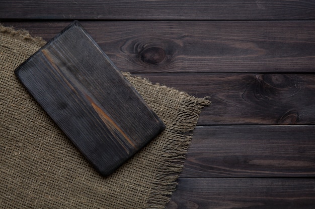 Empty cutting board on dark wooden table.