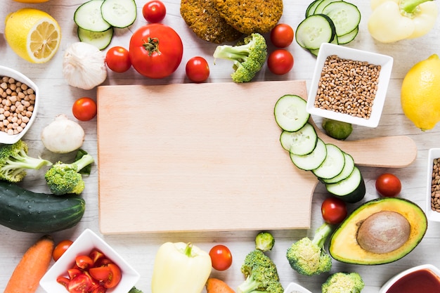 Empty cutting board surrounded by veggie food