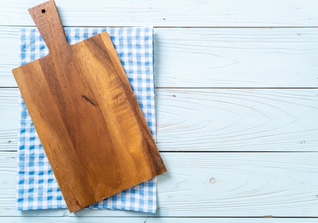 empty cutting wooden board with kitchen cloth on wooden background, top view