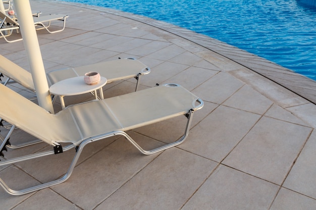 Empty deck chairs near the pool of a modern hotel