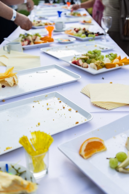 Empty dishes on long table in summer outdoor party