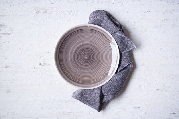 Empty earth tone plate with napkin on rustic grunge white wooden background.  