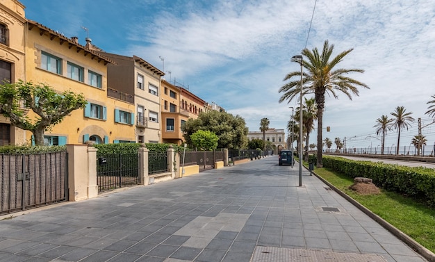 Empty embankment with palms and old buildings in Vilassar de Mar on sunny day Popular touristic location of Catalonia for vacation spending