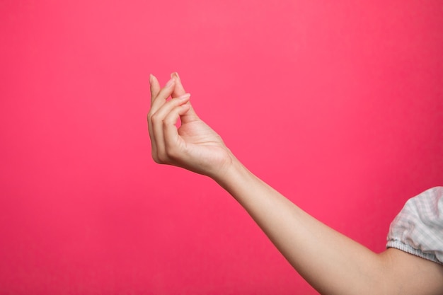 Empty female hand pretending holding something, isolated on pink background