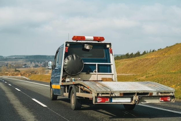 Empty flatbed tow carrier truck empty car carrier and flatbed tow truck vehicle travelling on a national road