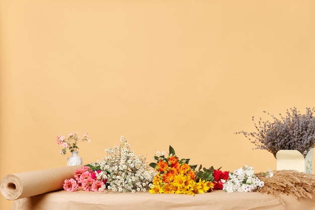 Empty florist workplace with many different flowers on table isolated over beige copy space background advertisement area mockup for promotion